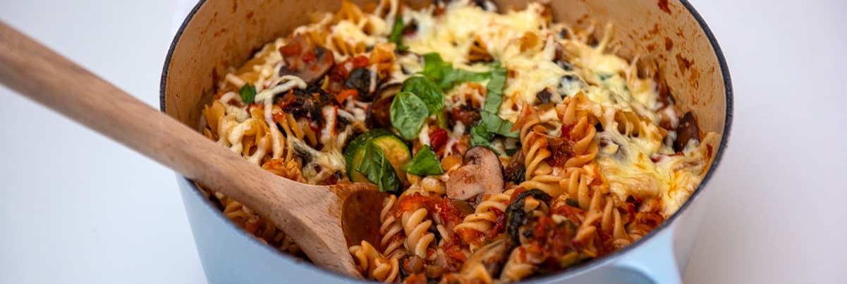 Pot of pasta with sauce and wooden spoon